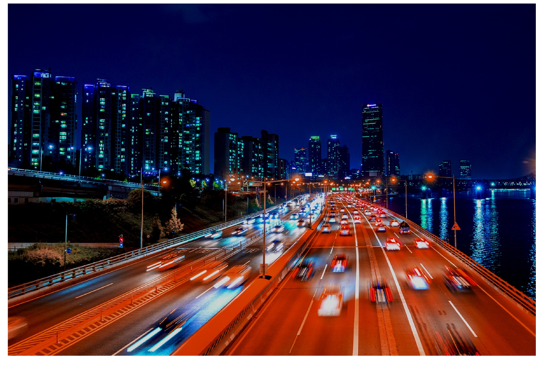 Rodovia com tráfego intenso à noite e skyline da cidade ao fundo